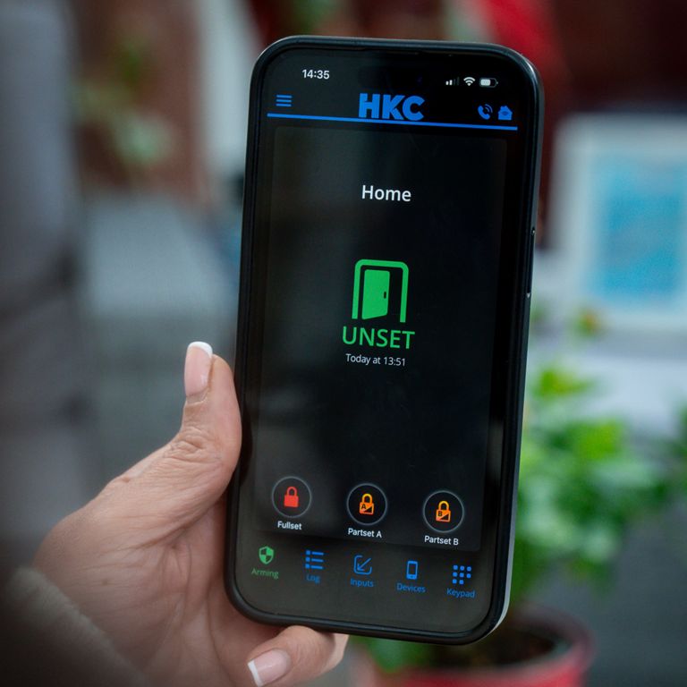 Official HKC marketing photograph showing the alarm app on a phone